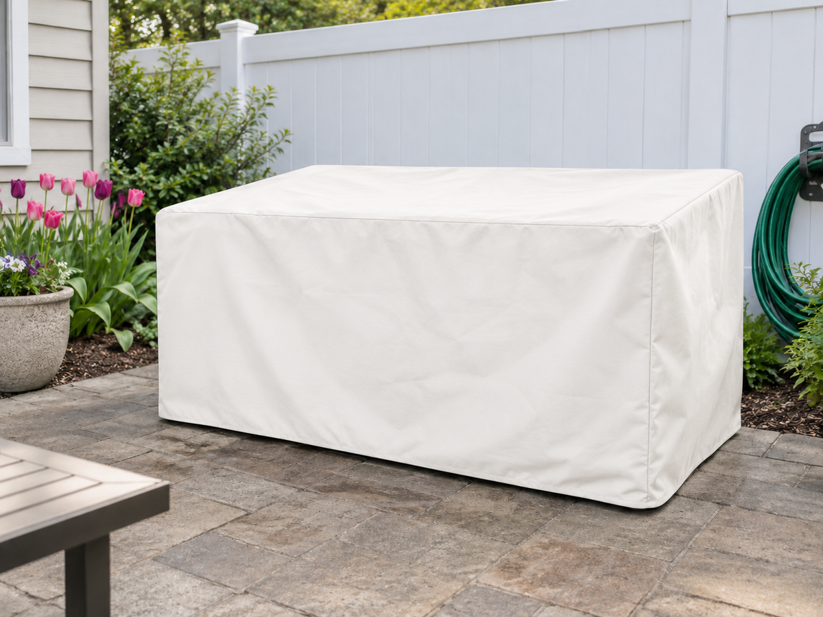 Light fabric cover over a closed rectangular storage box on a garden patio